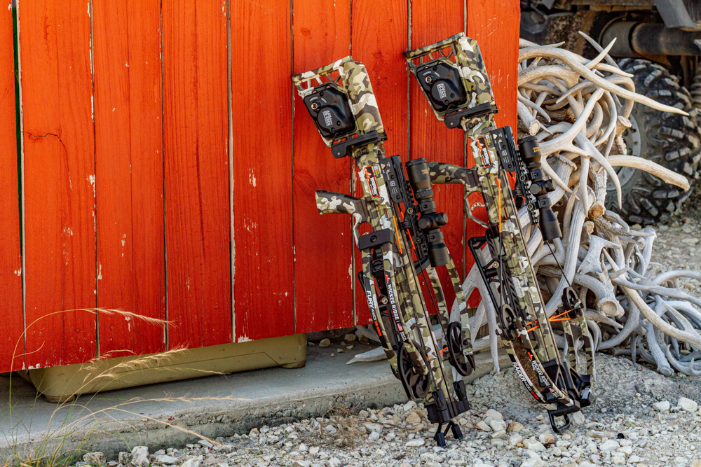 Two crossbows leaning against red fence