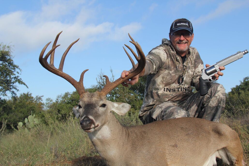 Hunter holding whitetail with hunting handgun